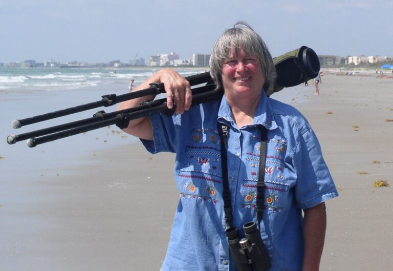 Council Member, Laurilee Thomson, holding her camera on a beach.